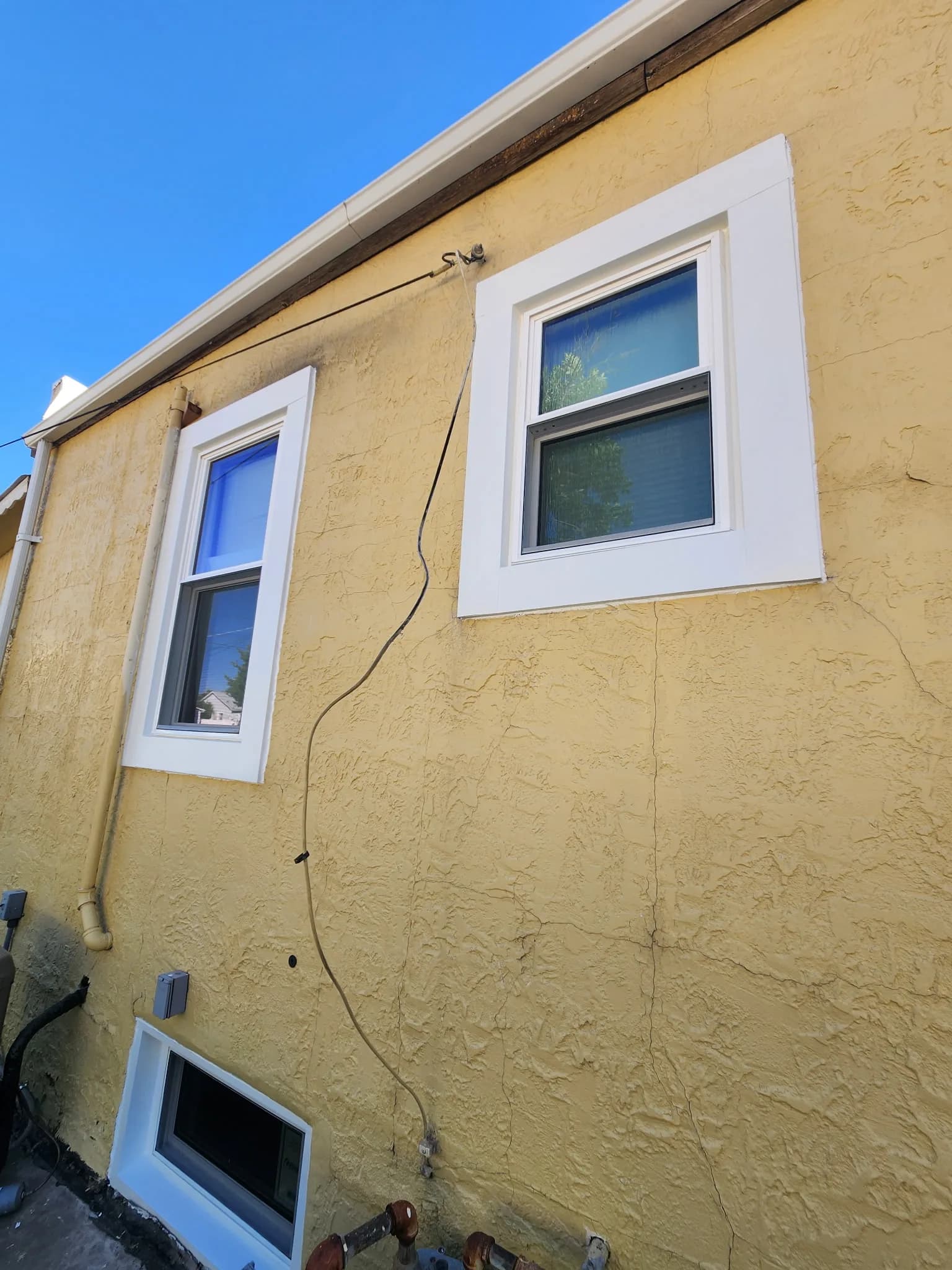 Small basement window on a stucco home exterior in Western Colorado